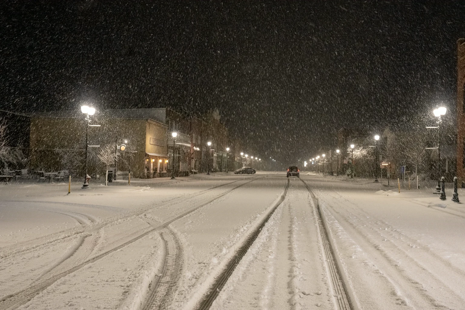 A mountain town main street under falling snow at night