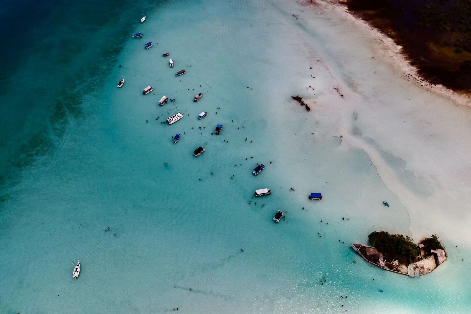 Boats on a sandbar in turquoise water from the air
