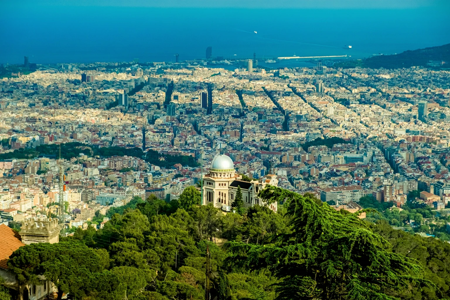The Eixample grid running down to the port and the sea, seen from Tibidabo past the dome of the Fabra Observatory