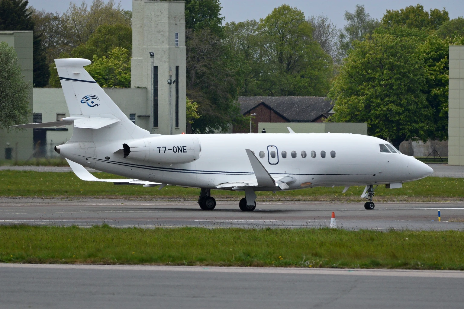 A white Dassault Falcon 2000LX taxiing past the old RAF buildings at Biggin Hill