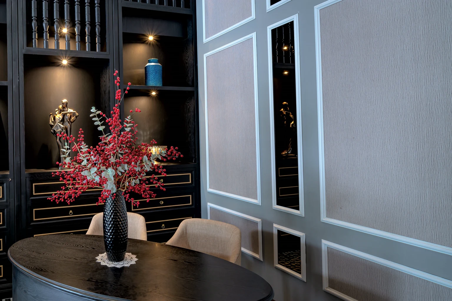 A private selling room with black lacquer cabinets, lit niches and two chairs at an oval table
