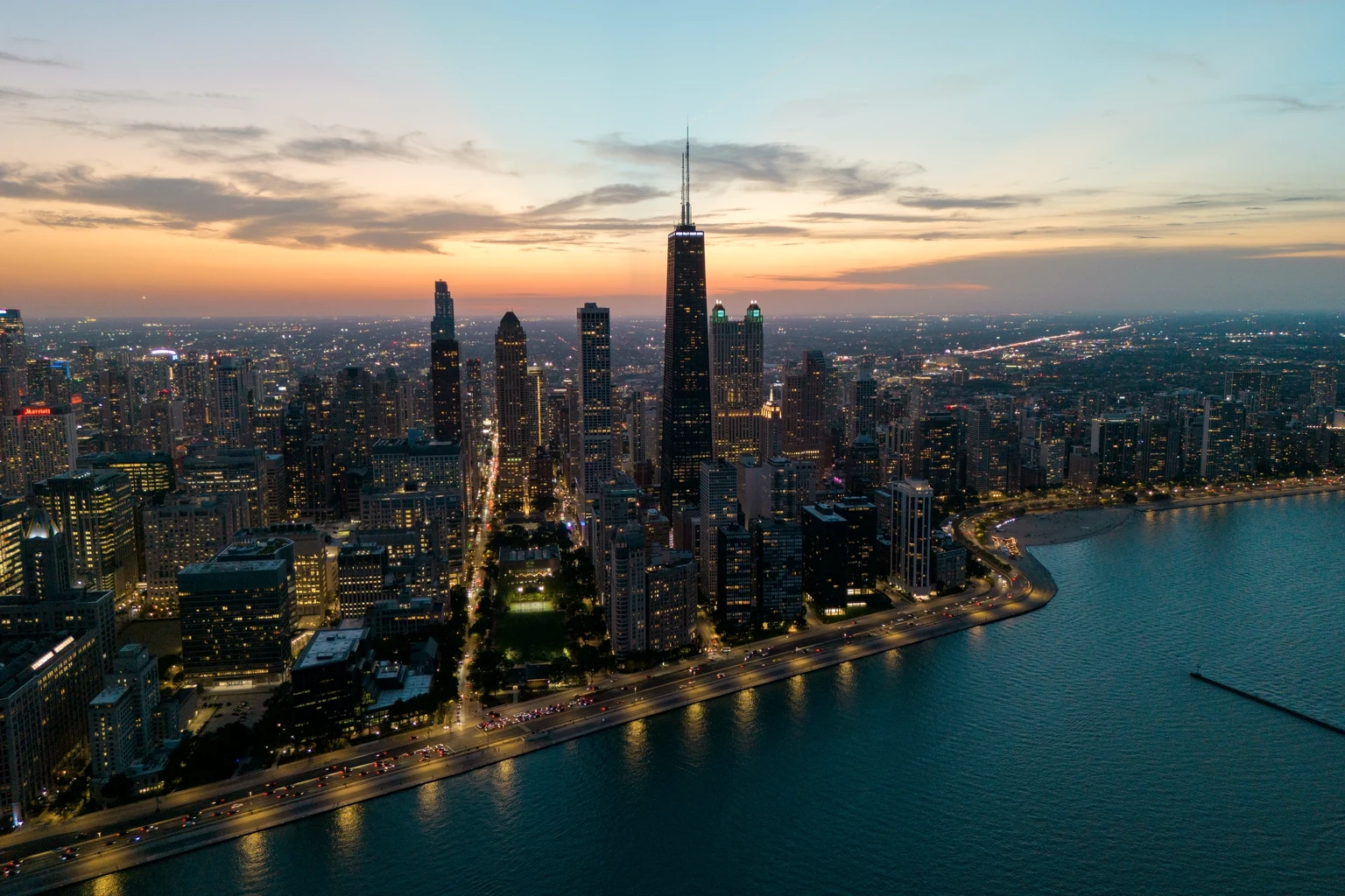 Chicago from the air at dusk, the Hancock Center above the Gold Coast and Lake Shore Drive curving along Lake Michigan