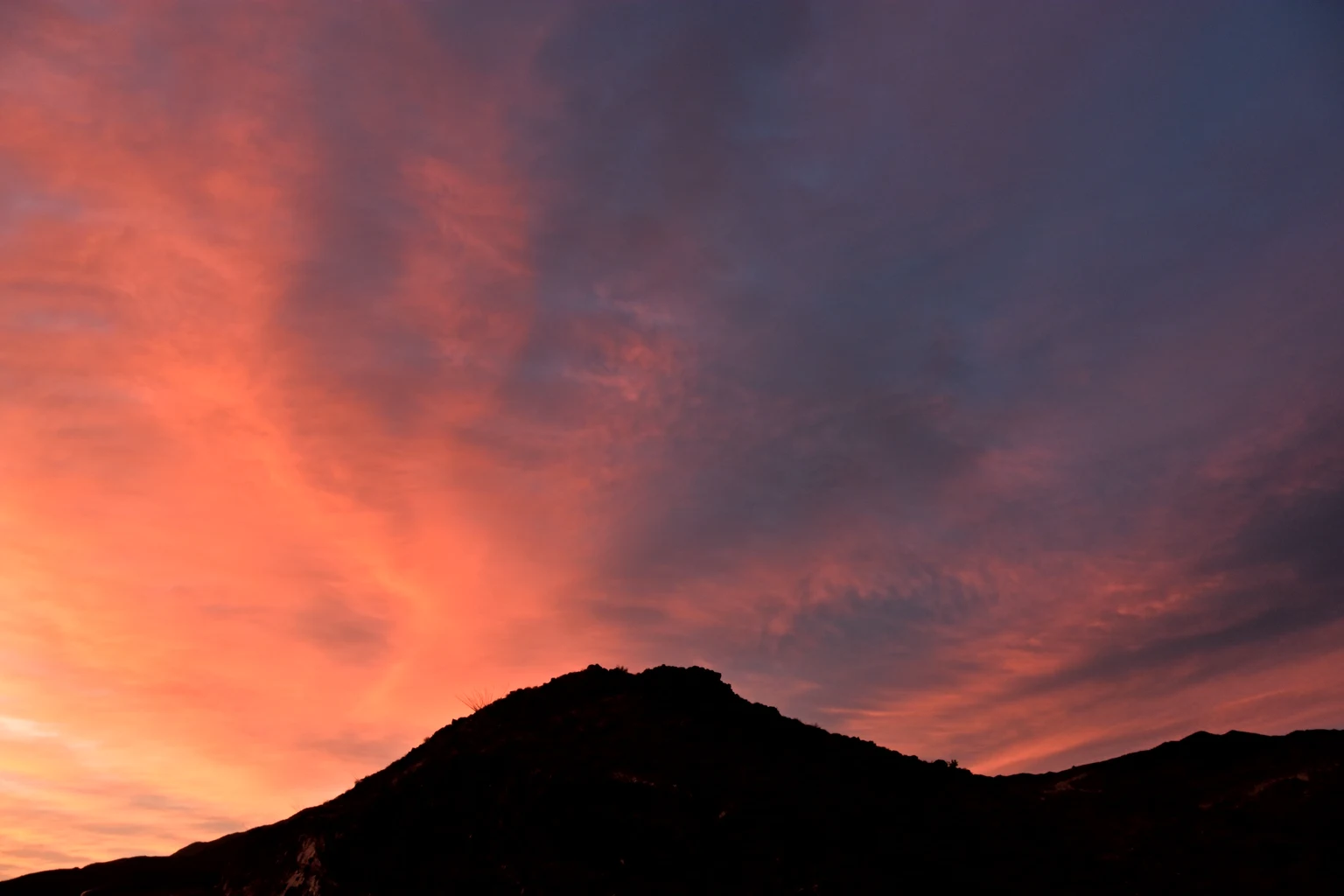 Sunrise over the Coachella Valley, a dark ridge under a red and violet sky