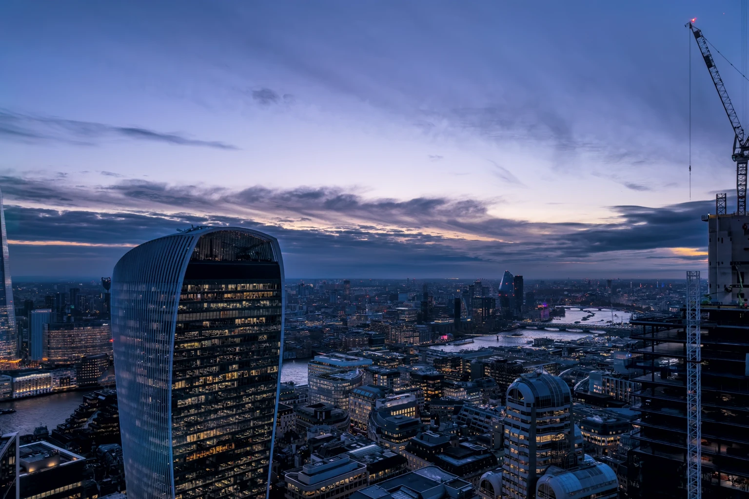 London office towers lit in the evening, seen across the river