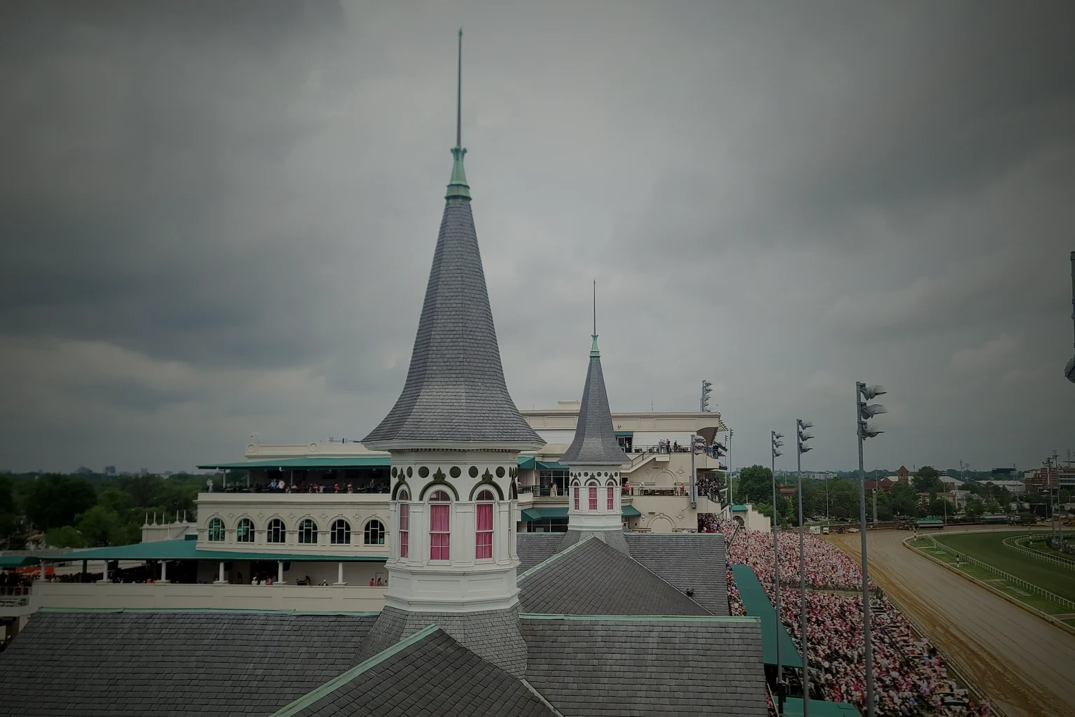 The twin spires of Churchill Downs on a race day, the grandstand full and the dirt track running away to the right