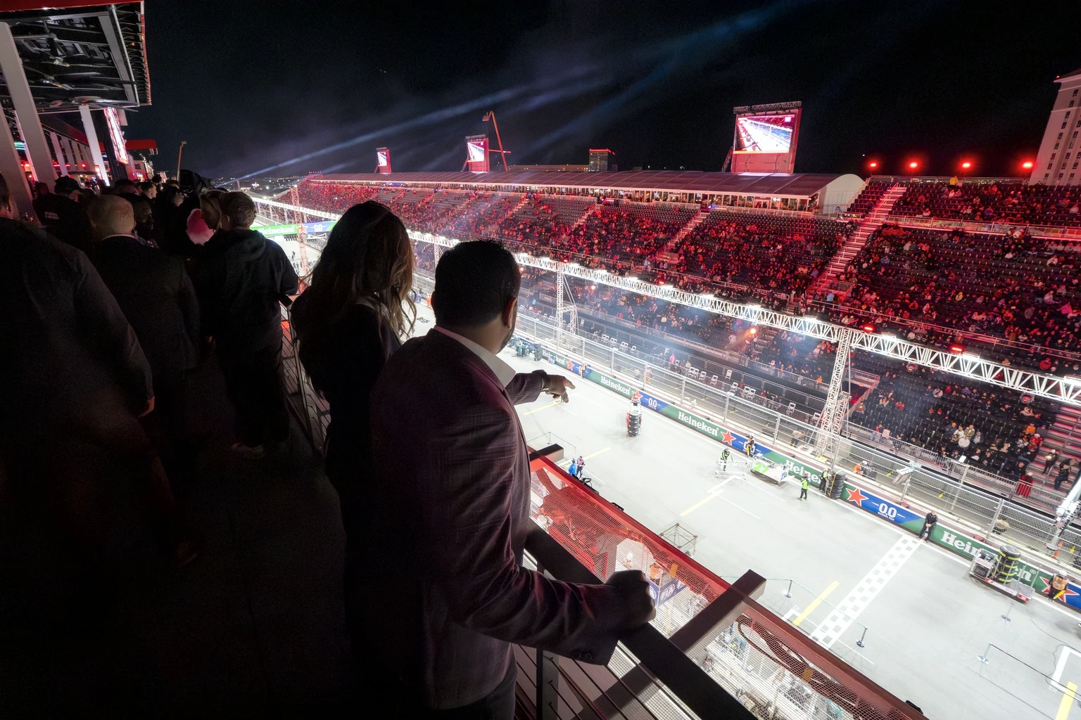 Guests on a hospitality balcony above the start-finish straight at the Las Vegas Grand Prix at night, the grandstand full opposite