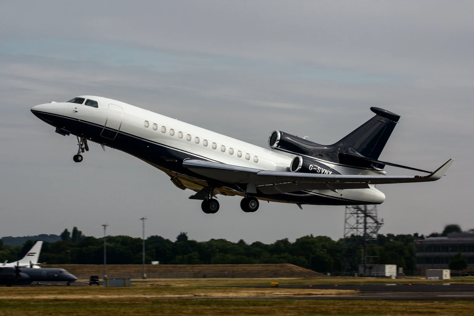 A navy and white Dassault Falcon 7X lifting off from Farnborough