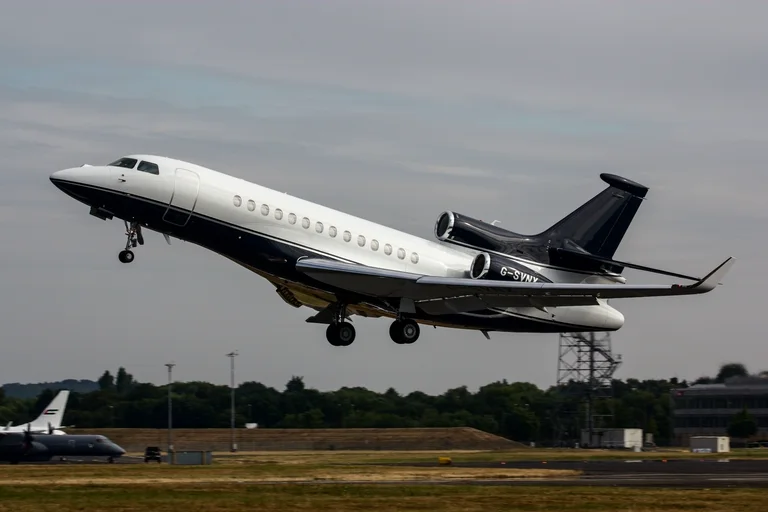 A navy and white Dassault Falcon 7X lifting off from Farnborough