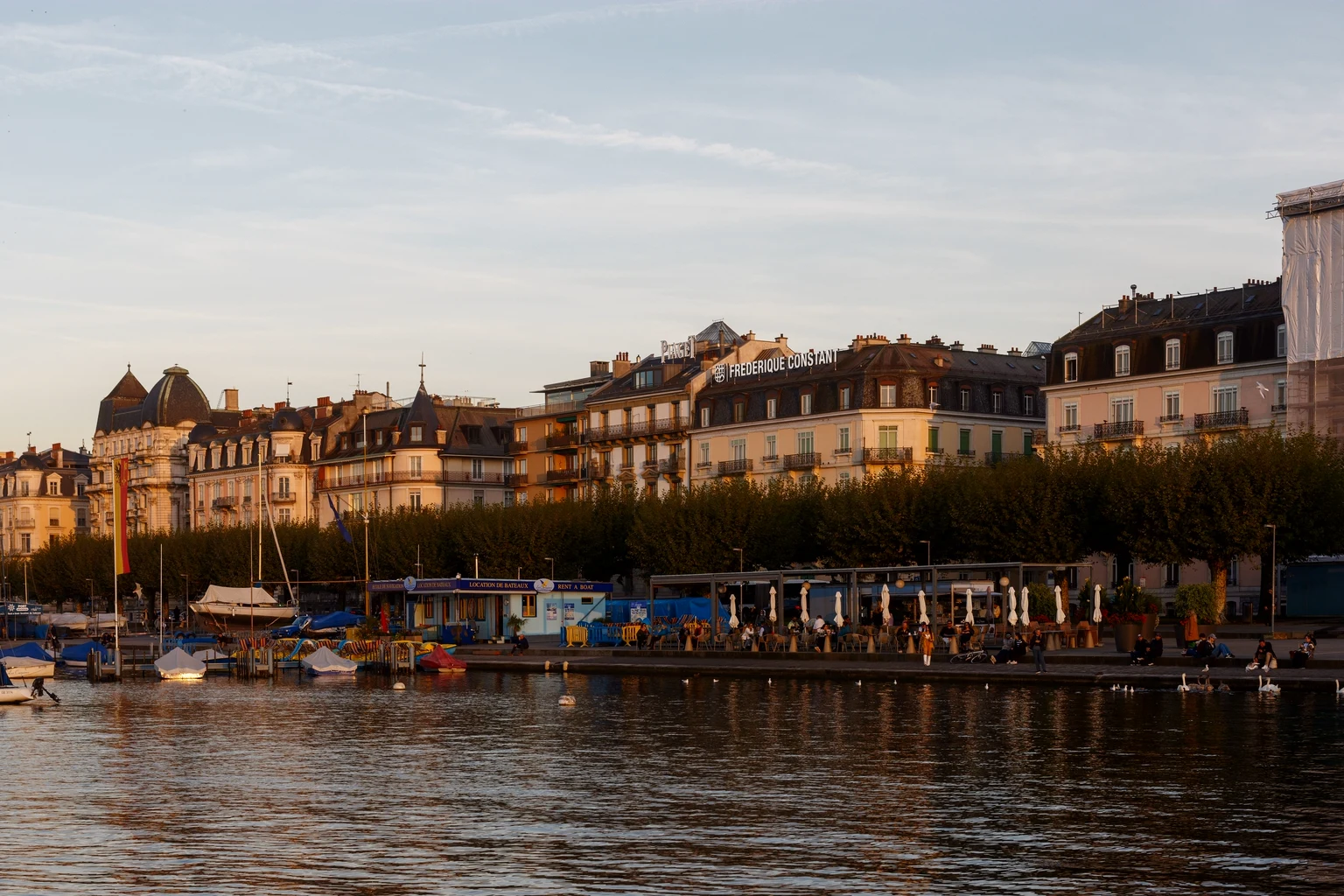 Geneva's lakefront facades and moored boats in golden evening light