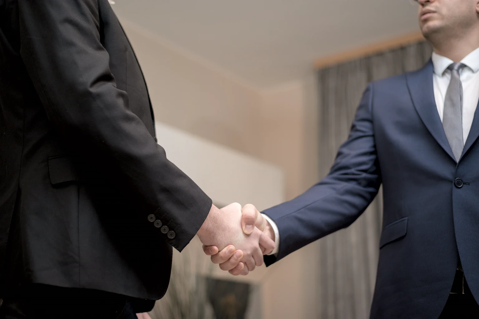 Two people in dark suits shaking hands