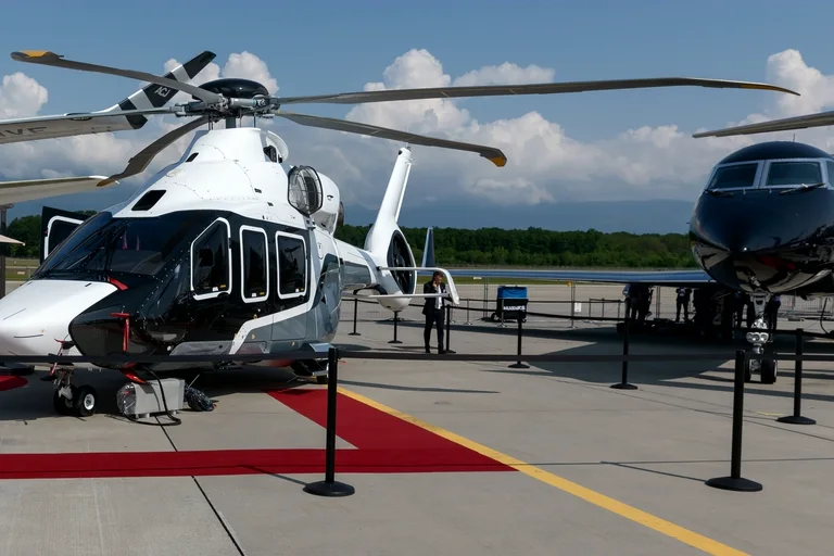 An Airbus ACH160 private helicopter in white and black on the static display at a business aviation show in Geneva