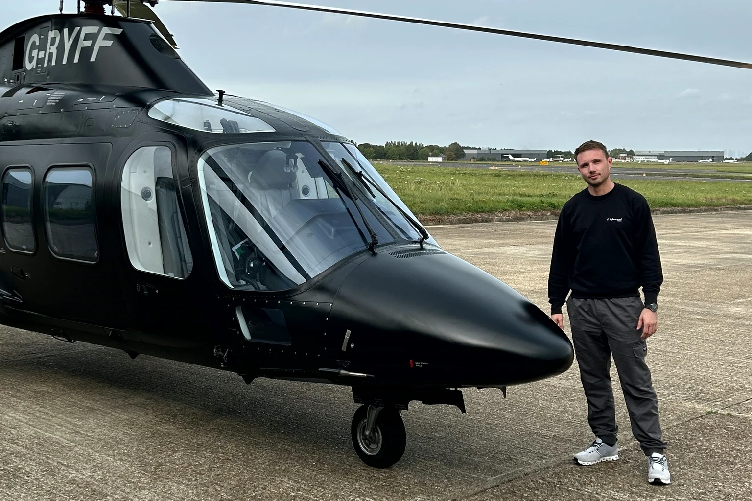 A black AW109 on the apron of a private airfield