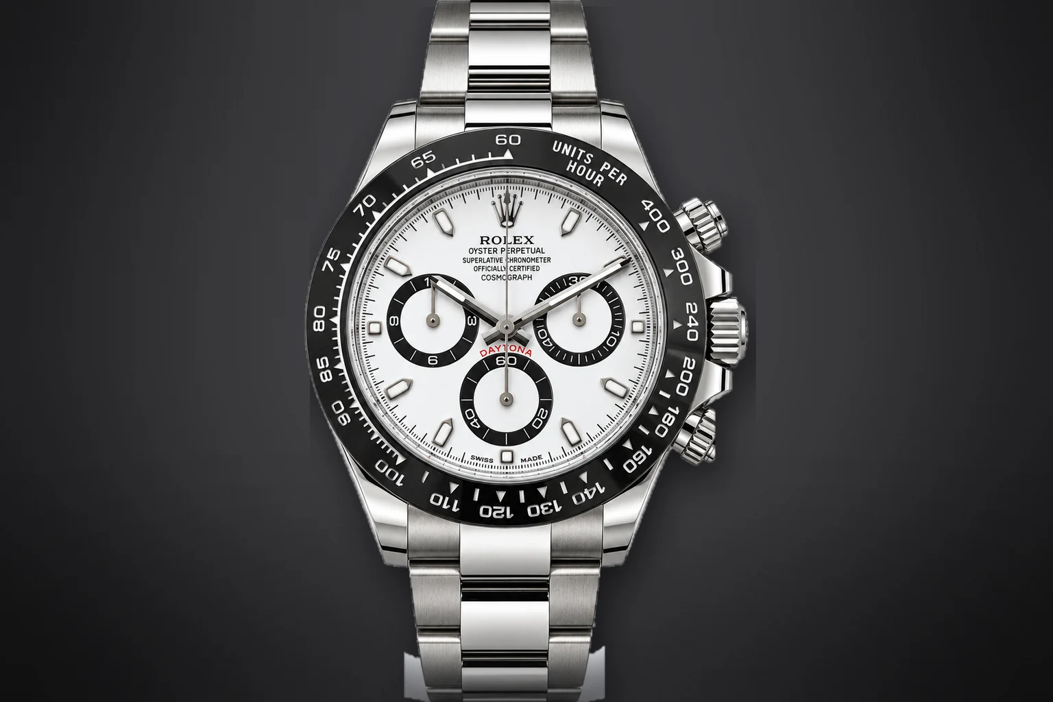 A steel Rolex Cosmograph Daytona with a white dial, black contrasting counters and a black ceramic bezel, lit against a dark ground