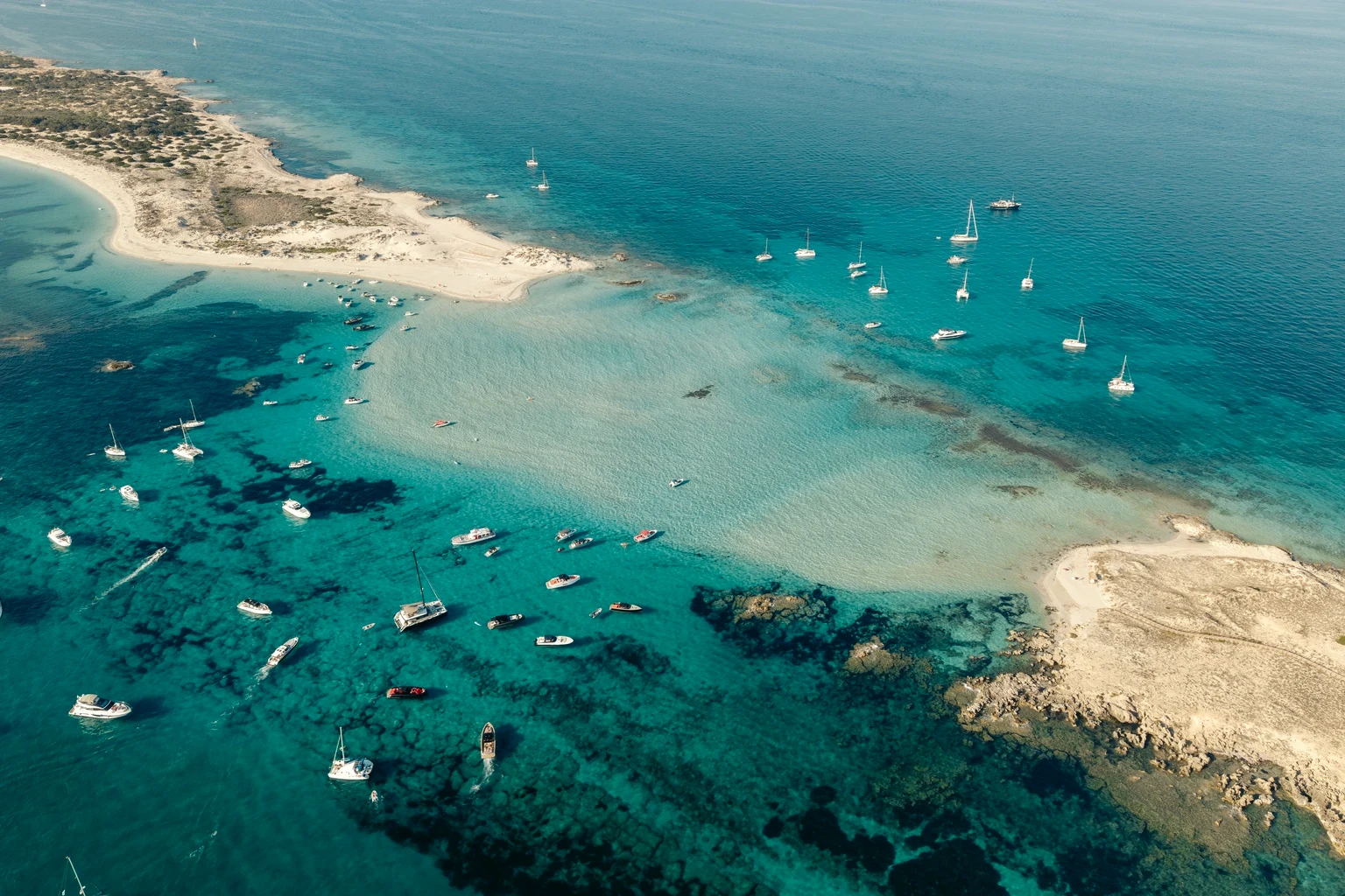 Boats anchored off Formentera in turquoise water from the air