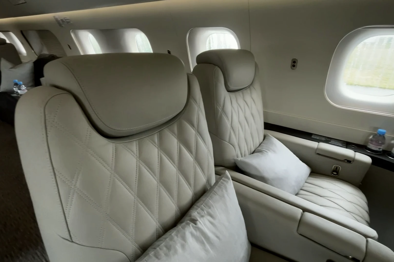 Quilted cream leather seats in a private jet cabin, daylight through the windows