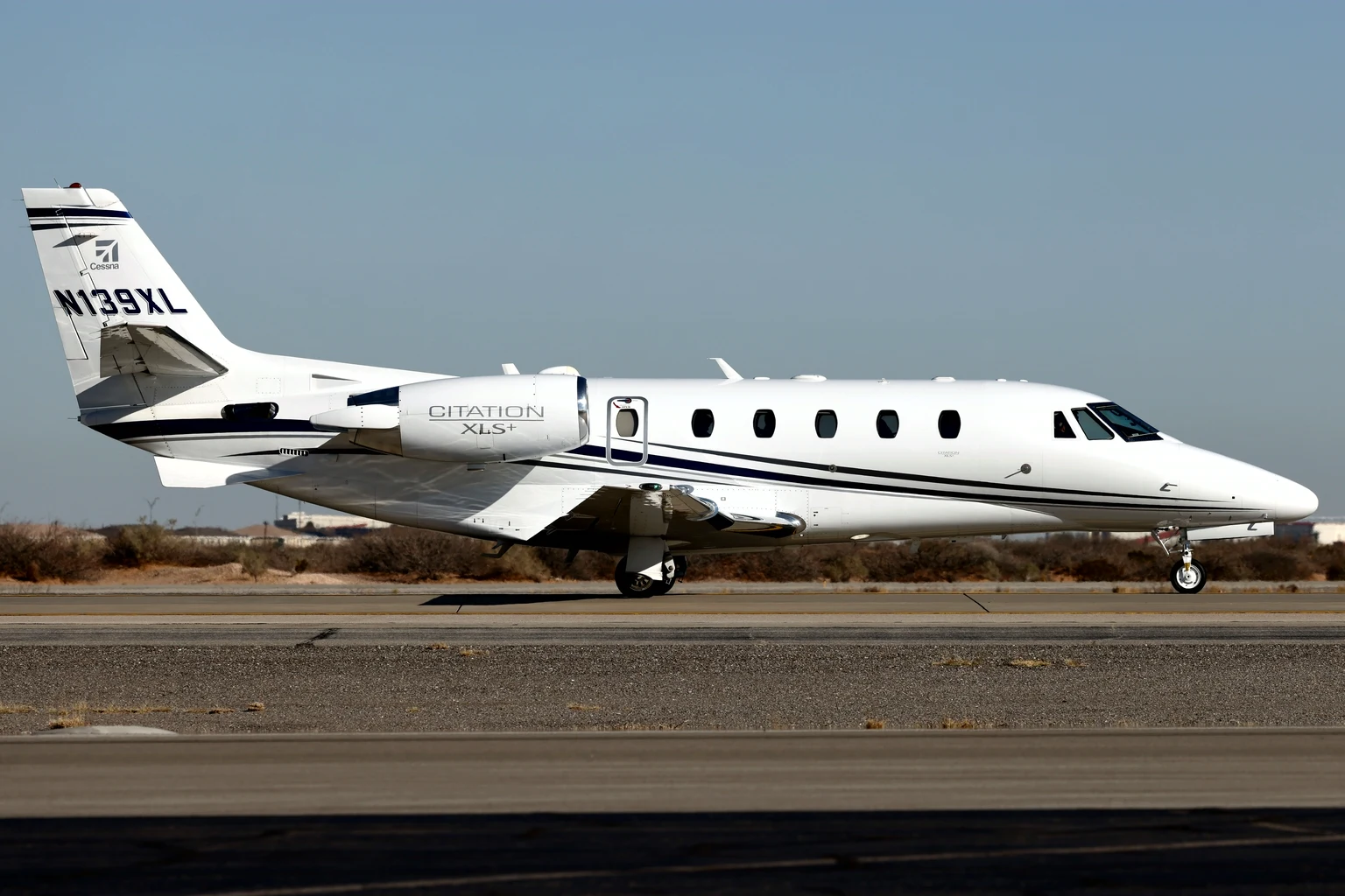 The Textron Citation XLS+ demonstrator, white with black stripes and 'Citation XLS+' on the engine, rolling side-on on a desert runway in bright sun, El Paso.