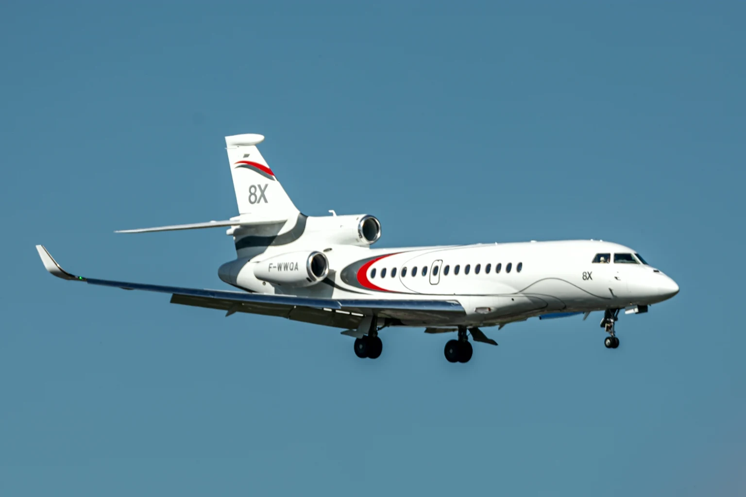 The Dassault Falcon 8X demonstrator in its white, grey and red '8X' livery in flight at the Paris Air Show, blue sky.
