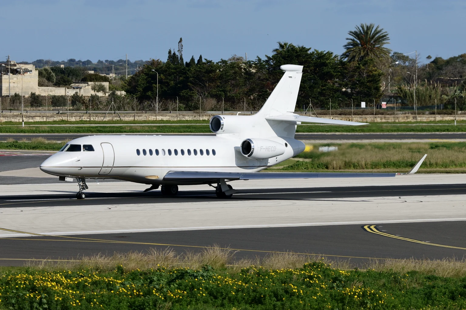 A Falcon business jet taxiing past the grass on a clear day