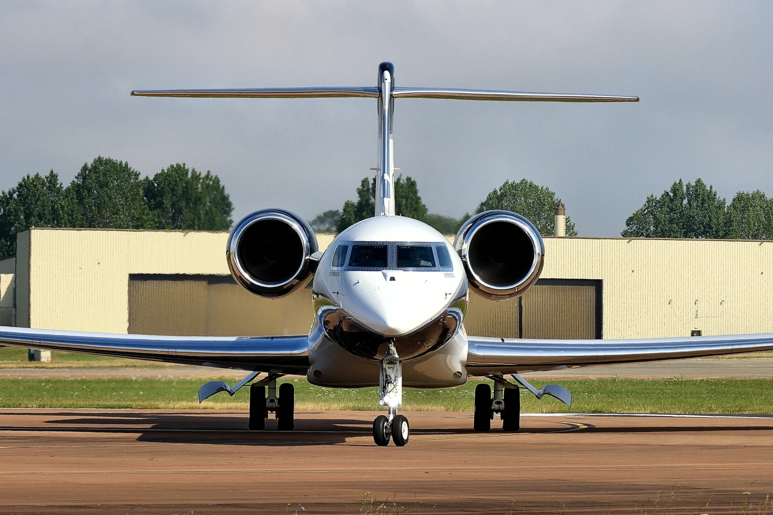 A Gulfstream G700 in Gulfstream's polished white and chrome livery taxiing head-on at RIAT, both engines and the T-tail framed symmetrically.