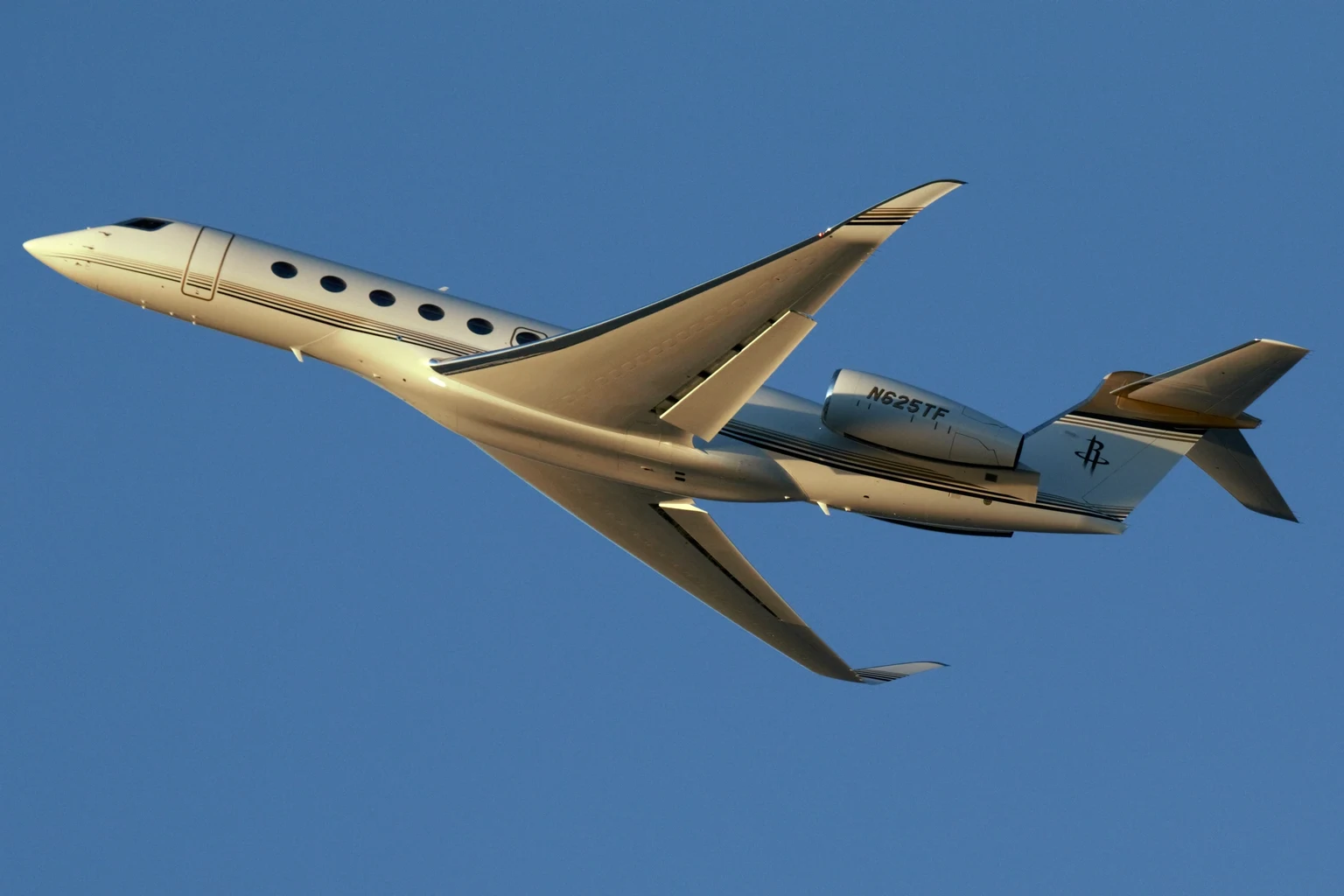 A white G700 climbing in golden light against a deep blue sky.