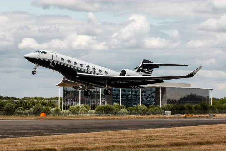 A Gulfstream G650 lifting off past Farnborough Airport's glass terminal