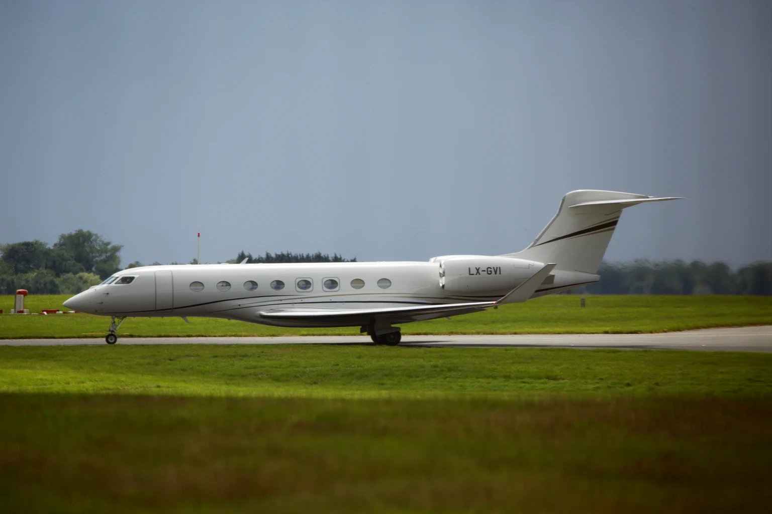 A Gulfstream G650 taxiing at London Stansted under a dark sky