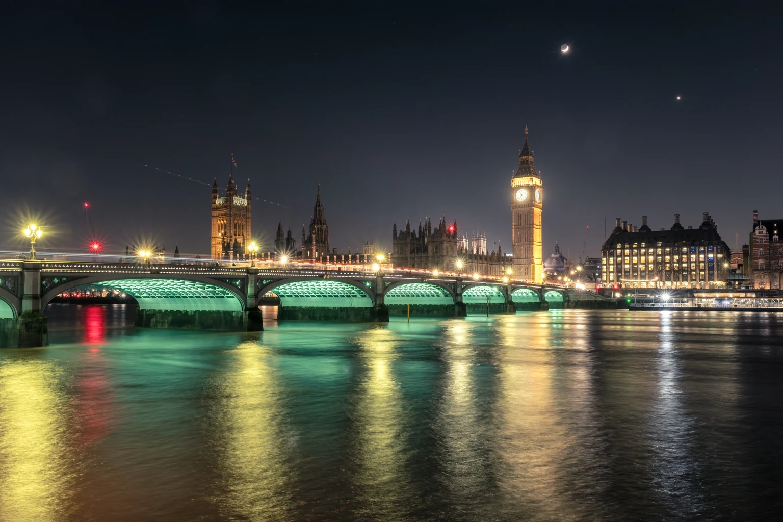 Westminster Bridge and the Houses of Parliament lit at night, reflected in the Thames