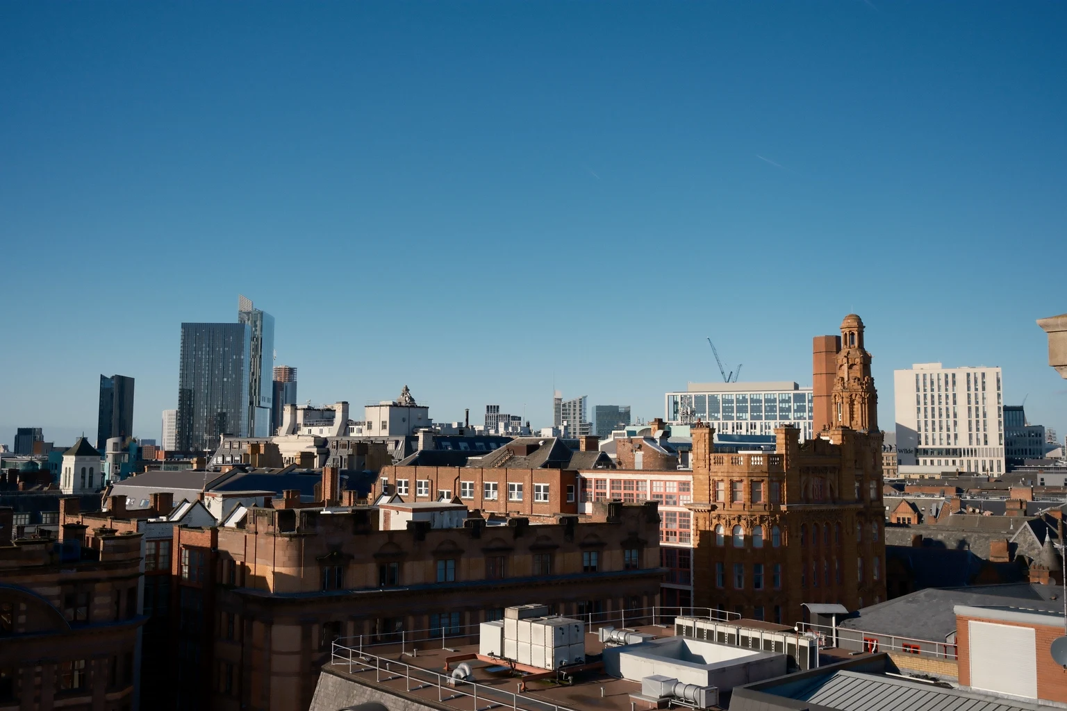 Manchester's rooftops at dusk with the towers behind