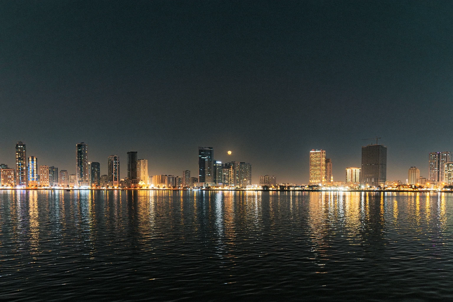The Miami skyline at night, mirrored in the still water of Biscayne Bay