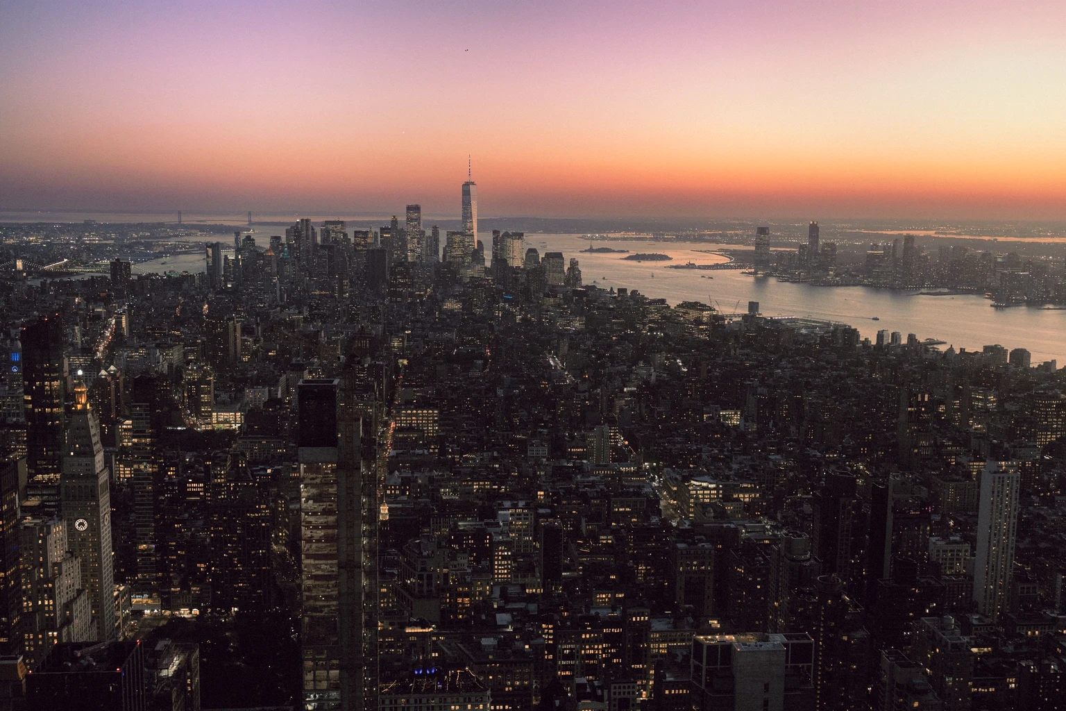 Manhattan from the air at dusk, the island stretching to the harbour