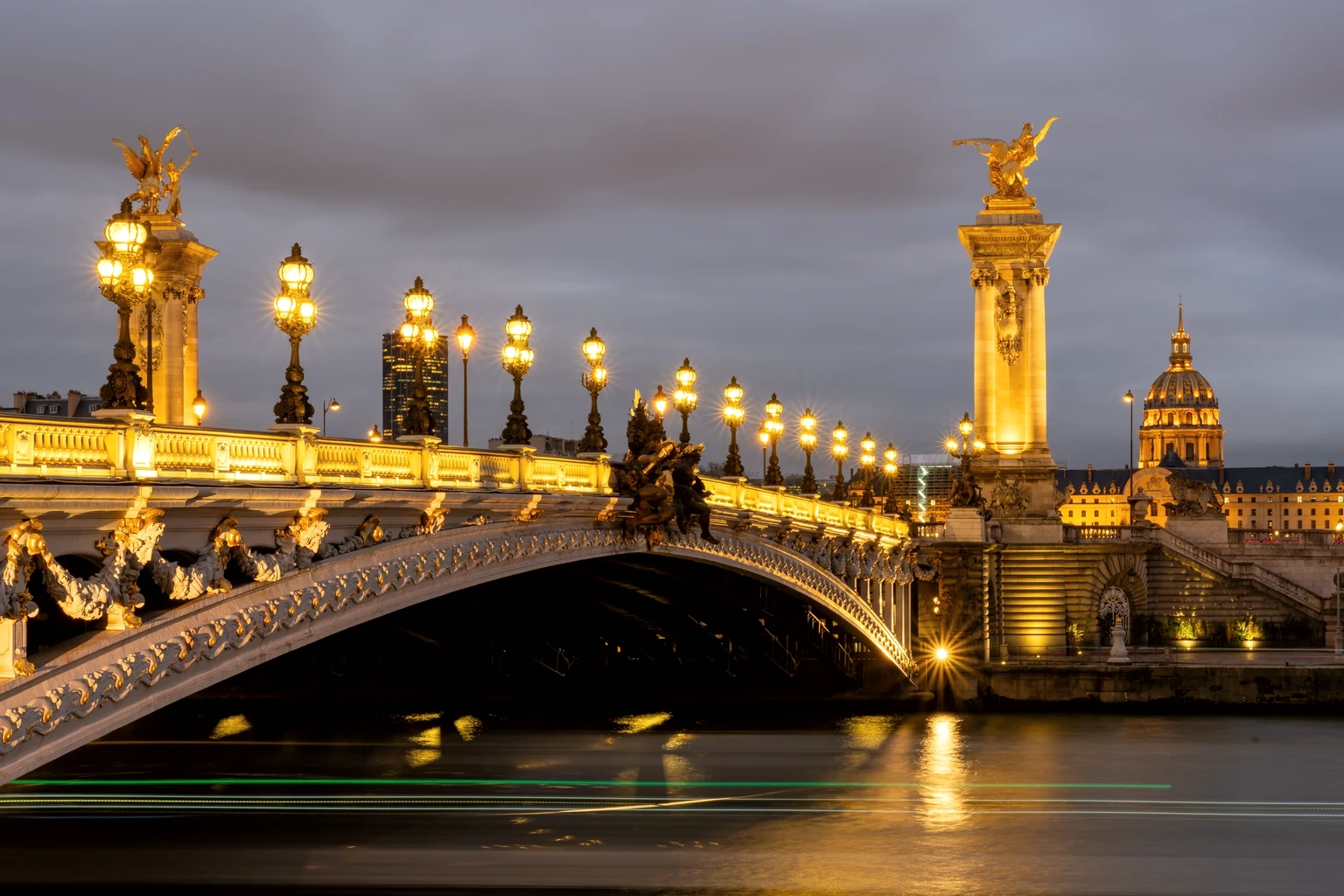 Pont Alexandre III lit at night, the dome of Les Invalides behind