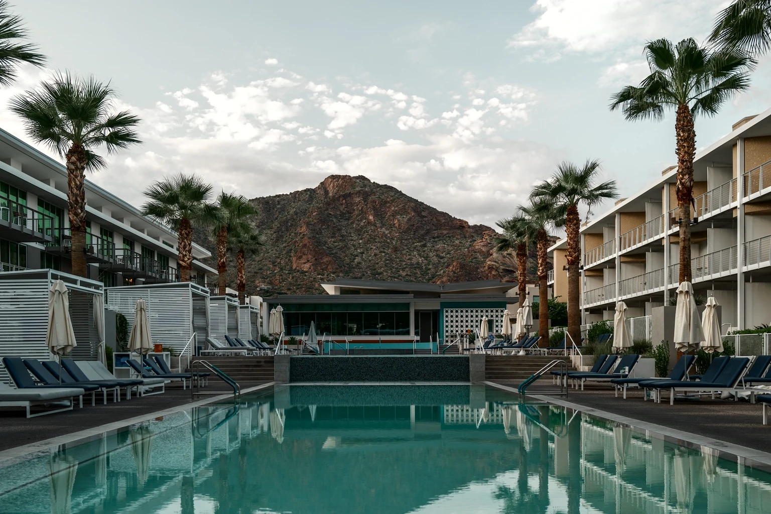 A resort pool between palms in Paradise Valley, Camelback Mountain beyond