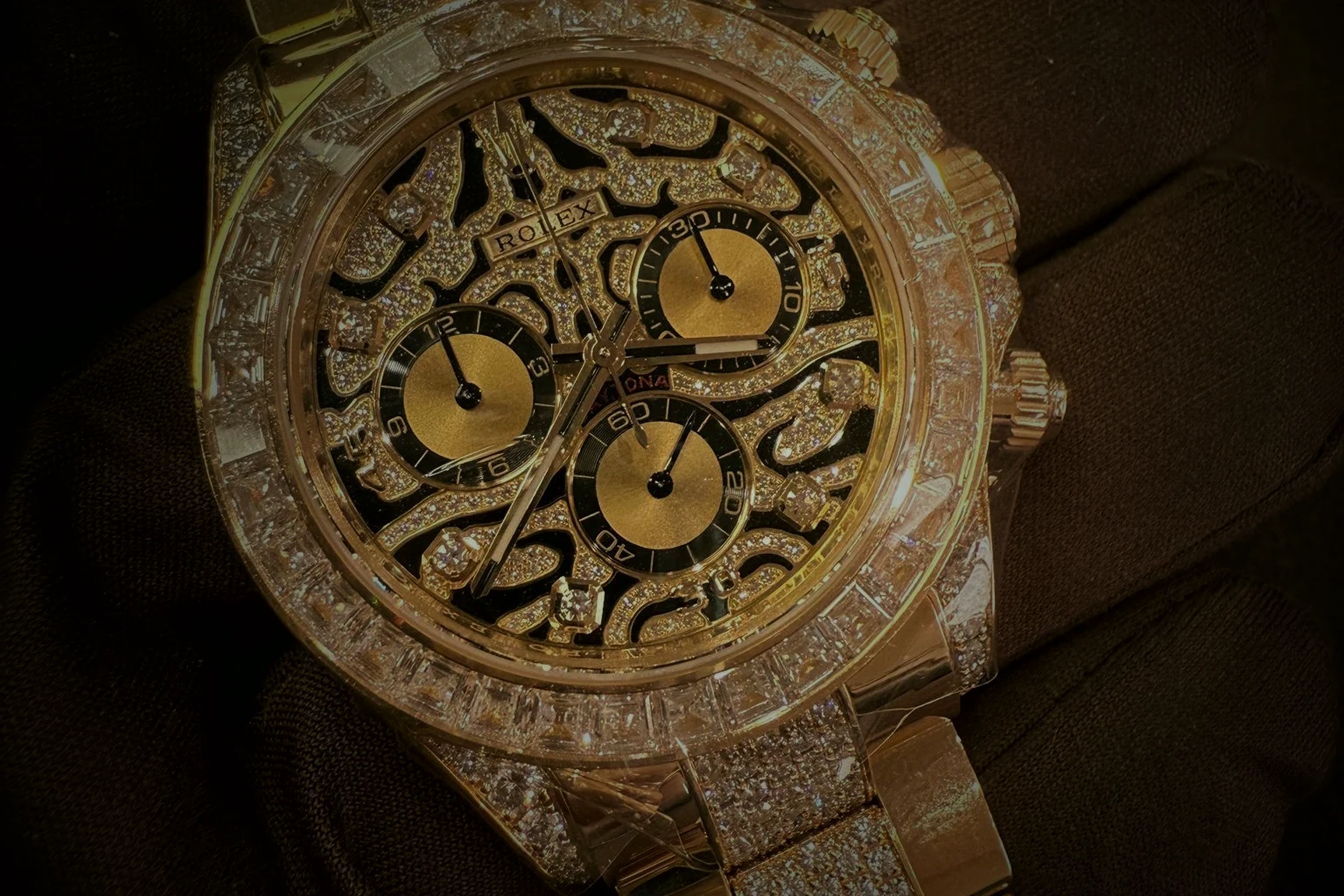 A gem-set yellow gold Rolex Daytona held in a gloved hand