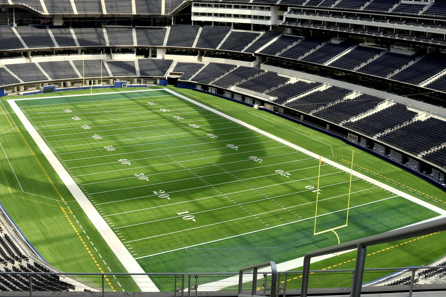 The empty bowl of SoFi Stadium seen from the suite-level railing, the field and the tiers below
