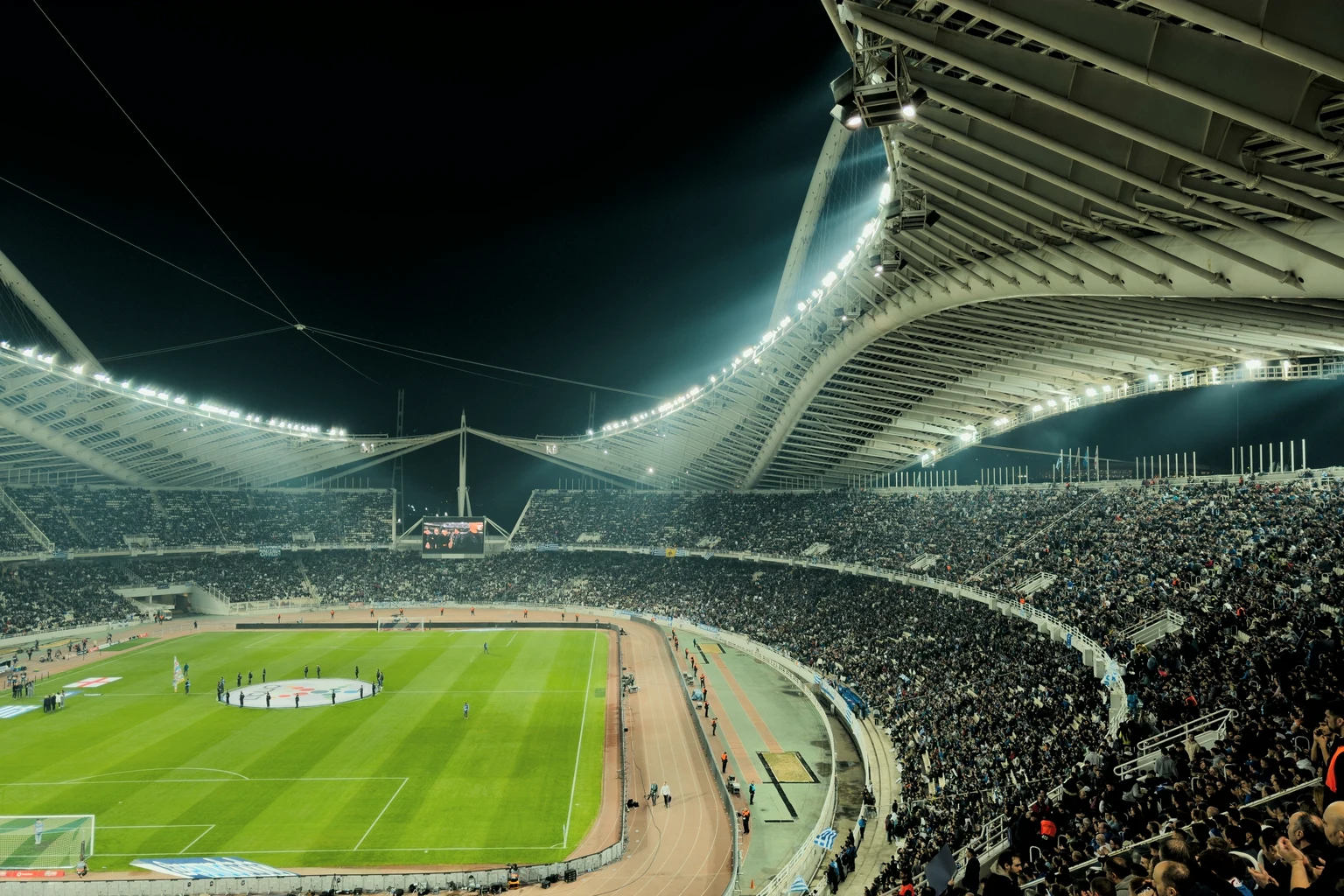 A full stadium at night under a sweeping lit roof