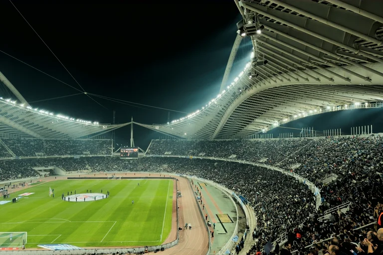 A full stadium at night under a sweeping lit roof