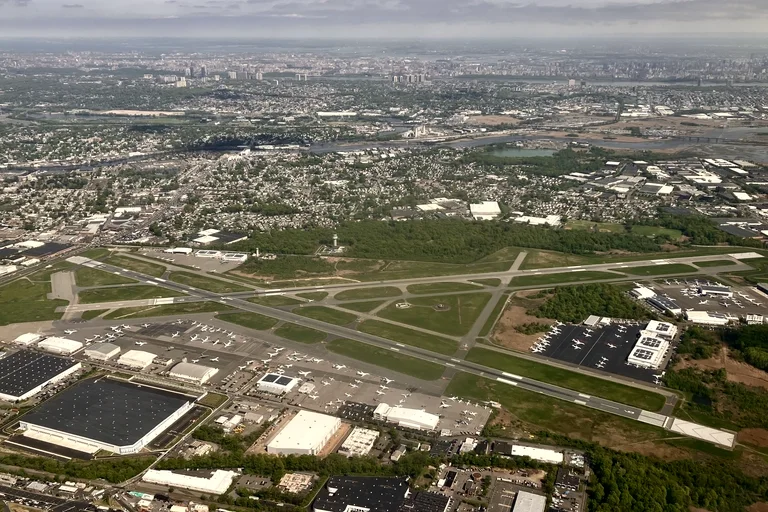 Teterboro Airport from the air, its ramps lined with business jets and the Manhattan skyline on the horizon