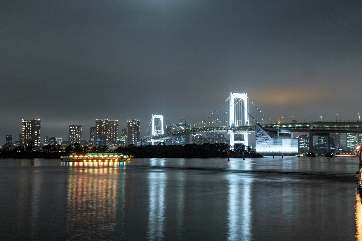 The Rainbow Bridge lit at night across Tokyo Bay
