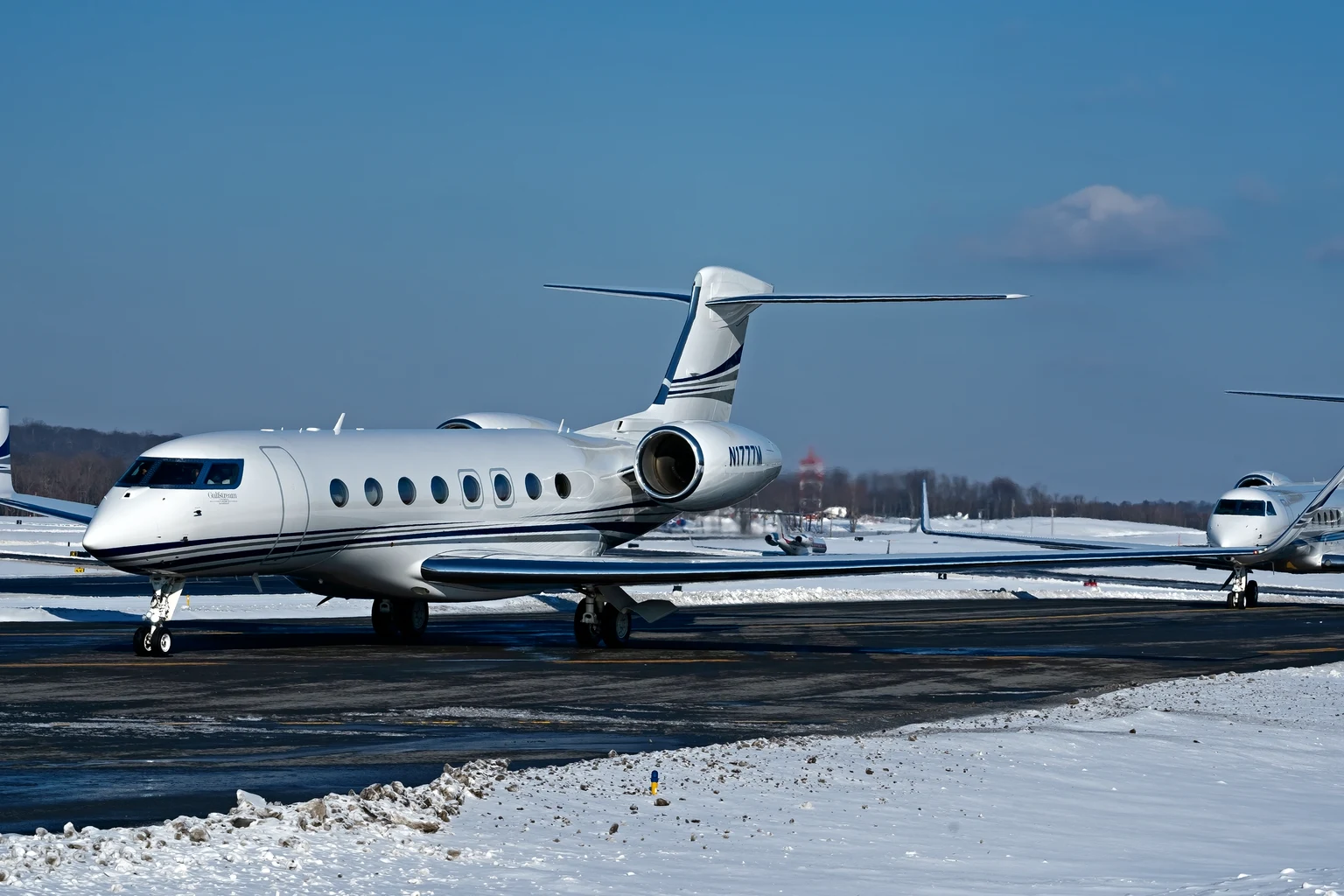 A Gulfstream G650ER taxiing for departure at Westchester County Airport after snow, a second Gulfstream behind it
