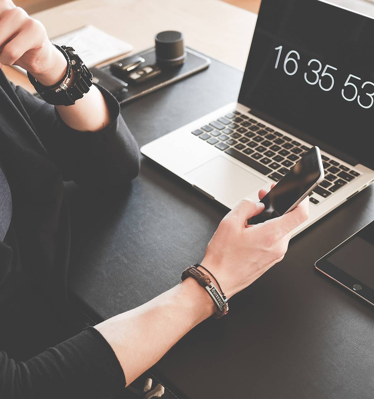 A woman providing services is sitting at a desk with a laptop and cell phone.