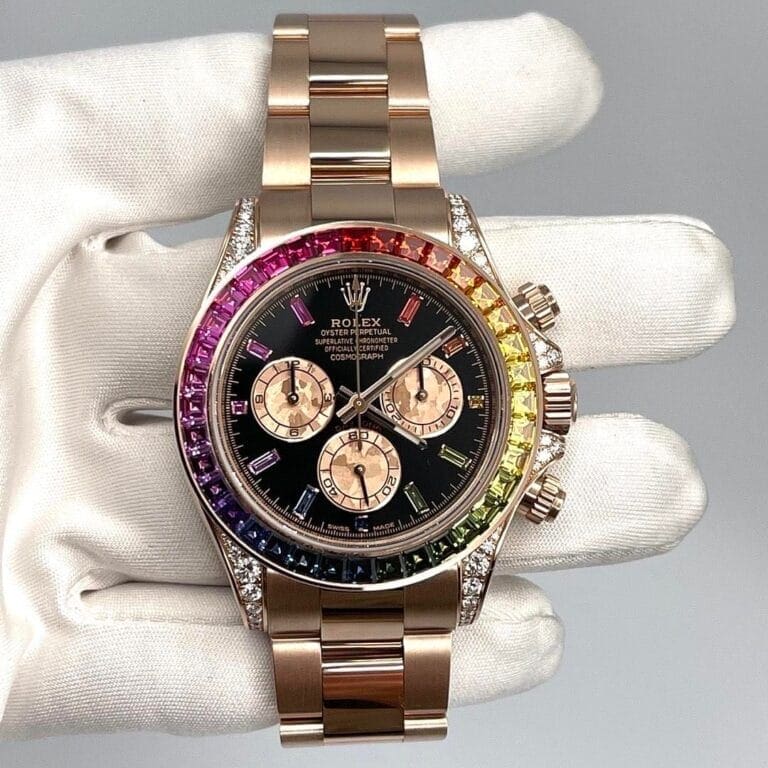 A gloved hand holding a rolex watch with a rainbow gemstone bezel and a black dial.
